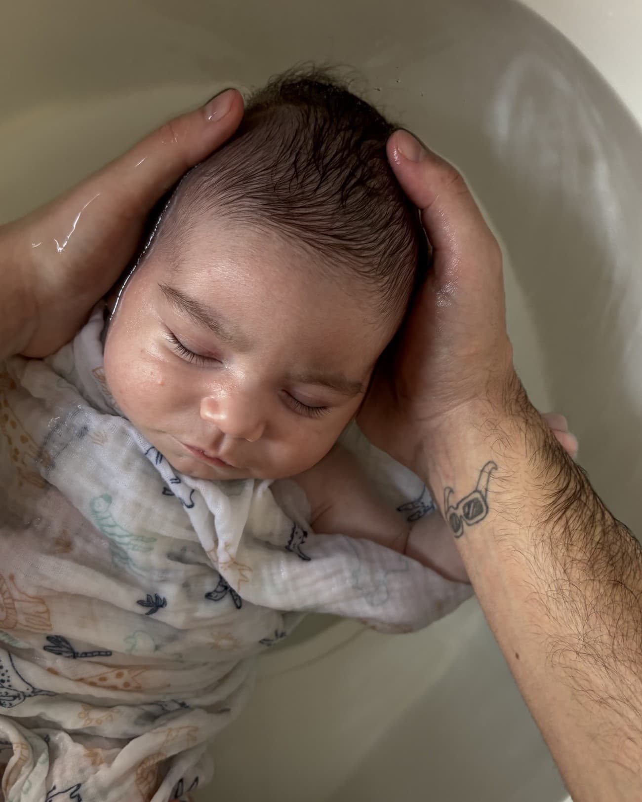 Parent tenant délicatement la tête de bébé pendant le bain enveloppé