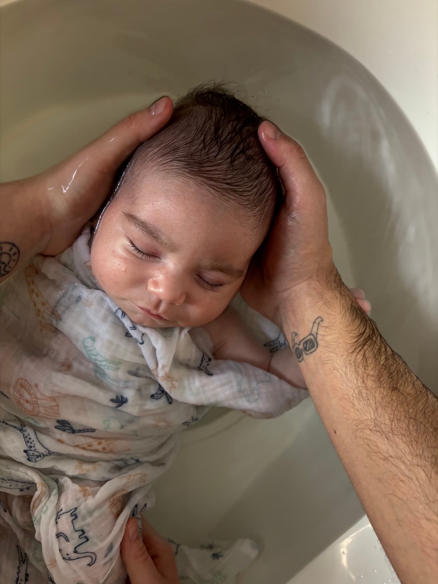 Parent tenant délicatement la tête de bébé pendant le bain enveloppé